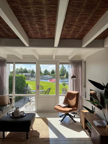 a living room with a chair and a sliding glass door at NIEUW Bootique Frysk huske Langweerderwielen in Boornzwaag