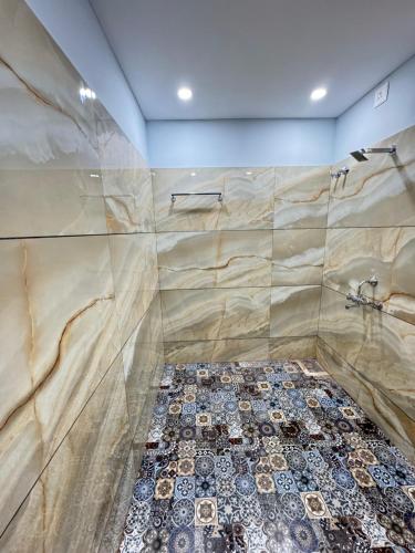 a bathroom with a shower with a tile floor at Suites by the Glasswater homestay in Kalyānpur