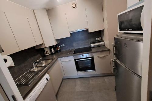 une cuisine avec des armoires blanches et un réfrigérateur en acier inoxydable dans l'établissement Spacious 3-bedroom apartment near the beach, à Le Touquet-Paris-Plage