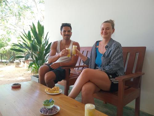 a man and a woman sitting on a bench drinking coffee at Yala wind in Tissamaharama