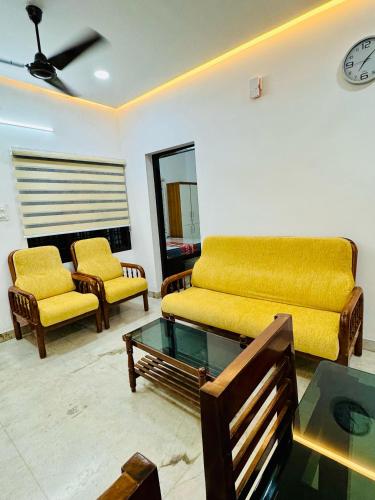 a living room with a yellow couch and chairs at Rahima Villa Ground floor in Cochin