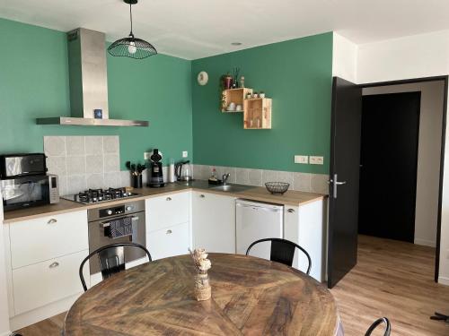 - une cuisine avec une table, des chaises et des murs verts dans l'établissement Appartement T2 Lamballe-Armor, à Lamballe Armor