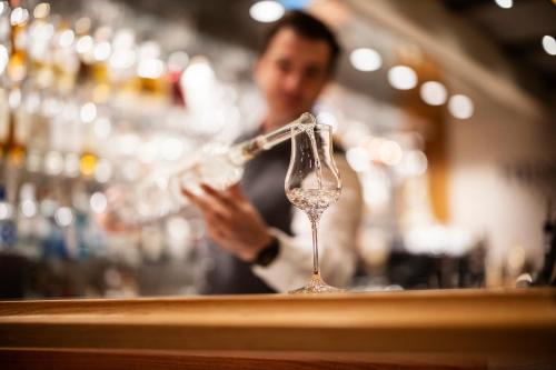 a man is standing behind a bar with a wine glass at Romantikhotel Platte in Attendorn