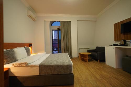 a hotel room with a bed and a chair and a window at Hotel Old Town in Batumi