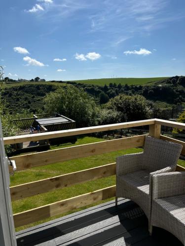 a porch with two chairs and a fence with a view at Valley View in Port Isaac