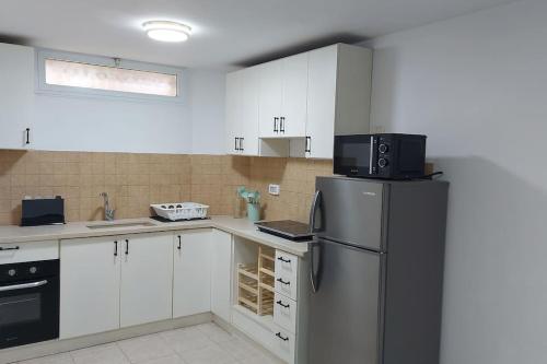 a kitchen with white cabinets and a black refrigerator at דירת נופש in Ramat Yishay
