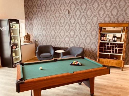 韦斯特雷费尔Hof Steinhütten Boutique Apartments的配有台球桌和两把椅子的房间