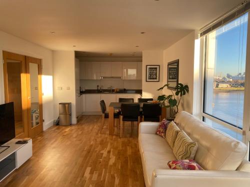 a living room with a white couch and a kitchen at River view spacious apartment in London