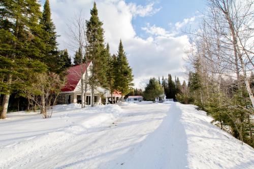 a snow covered road in front of a house at Aux Pignons Rouges Camping & Chalets in Saint Romain