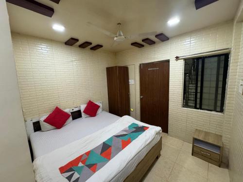 a bedroom with a bed with red pillows on it at Gandharva Residency Koregaon Park in Pune
