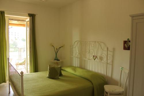a bedroom with a bed with a green bedspread at Le Rocce in SantʼAgata deʼ Goti