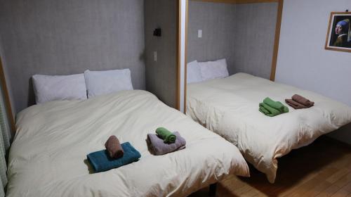 two twin beds with towels on them in a bedroom at 駅徒歩1分 観光拠点に最適なゆったり快適一軒家 in Osaka
