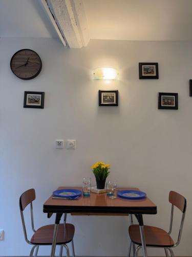 une table avec des chaises et une horloge sur un mur dans l'établissement Höd, à Ouistreham
