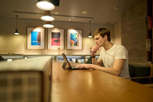 a man sitting at a table using a laptop computer at Hotel Resol Nagoya in Nagoya