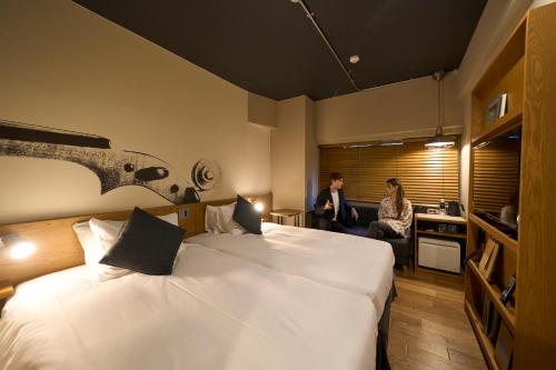 two people sitting in a hotel room with two beds at Hotel Resol Nagoya in Nagoya
