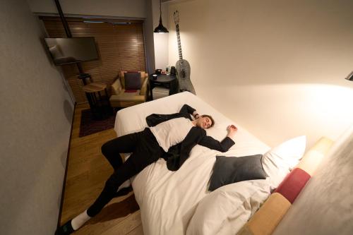 a man laying on top of a bed at Hotel Resol Nagoya in Nagoya