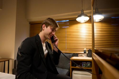 a young man talking on a cell phone at Hotel Resol Nagoya in Nagoya