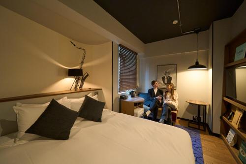 two women sitting in a room with a bed at Hotel Resol Nagoya in Nagoya