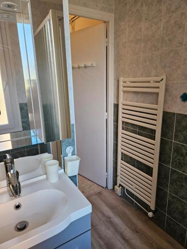 une salle de bain avec un lavabo blanc et un miroir dans l'établissement Appartement Banyuls sur Mer face à la mer, à Banyuls-sur-Mer