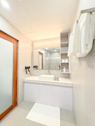 a white bathroom with a sink and a mirror at Raakani Dhigurah in Dhigurah