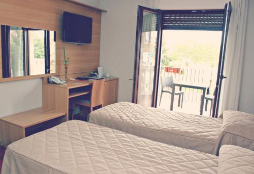 a hotel room with a bed and a desk and a window at Halanus Hotel And Resort in Alanno