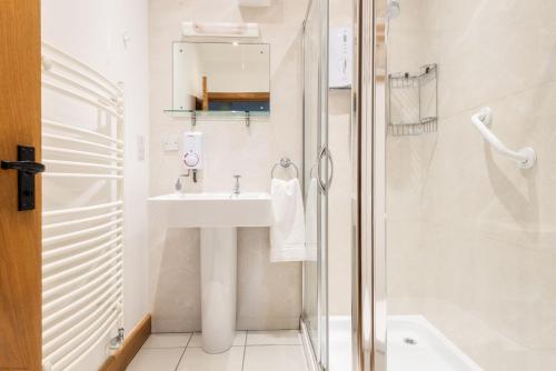 a white bathroom with a sink and a shower at East Trenean Farm Cottages -4 Luxury Cornish Cottages sleeping 20 with hot tubs, private gardens, rural views and EV facilities in Looe