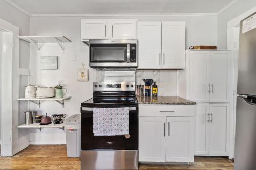 a kitchen with white cabinets and a black stove top oven at Charming Bungalow in McKinney – Walk to Downtown bungalow in McKinney
