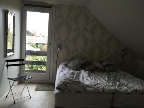 a bedroom with a bed and a window and a chair at Bagsværd Apartment in Hareskovby