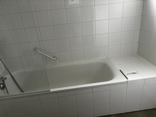 La salle de bains est pourvue d'une baignoire et de carrelage blanc. dans l'établissement Aureilhan T2 50m2, 6 pers, wifi, piscine résidence, à Aureilhan