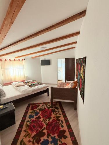 a bedroom with two beds and a rug at Gospodaria Klaus in Rozavlea