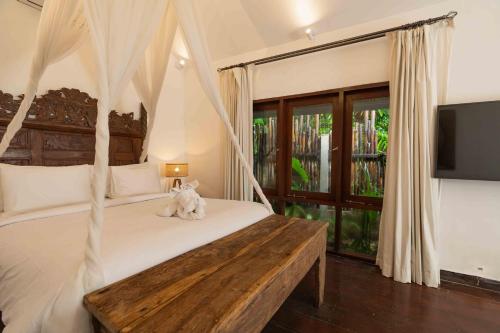 スミニャックにあるThe Gardens Seminyakのベッドルーム1室(ハンギングベッドフレーム付きの白いベッド1台付)