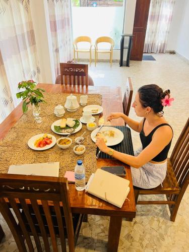 a woman sitting at a table eating food at Wild Blossom Sigiriya in Sigiriya