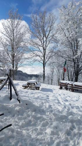 a picnic table and benches covered in snow at casa al taverni in Falciano
