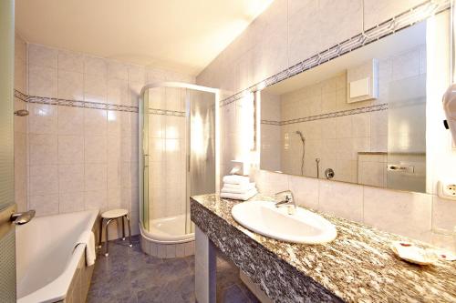 a bathroom with a sink and a bath tub and a tub at Alpenhotel Rieger in Mittenwald