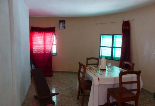 un comedor con una mesa con sillas y cortinas rojas en Chez Niominka Bi à Niodior, en Poundiougne
