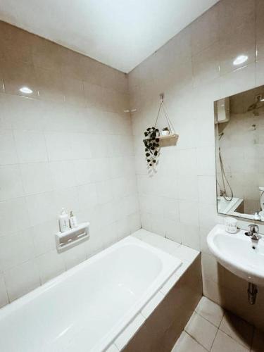a white bathroom with a tub and a sink at Premium Getaway in City Central in Jakarta
