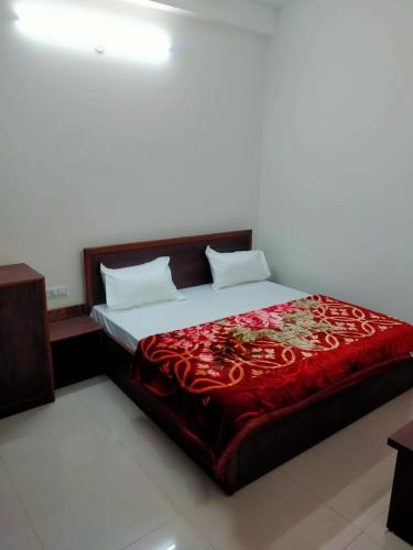 a bedroom with a large bed with a red blanket at Hotel moon river in Rāiwāla
