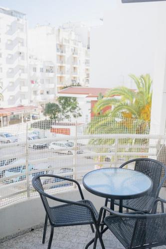 a table and chairs on a balcony with a view of a city at Beach Apartment in Armação de Pêra