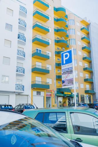 a parking lot with cars parked in front of a building at Beach Apartment in Armação de Pêra
