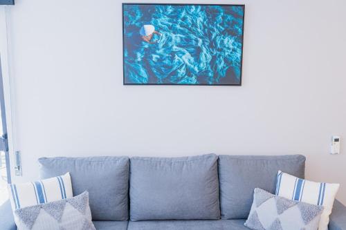 a blue couch in a living room with a painting on the wall at Beach Apartment in Armação de Pêra