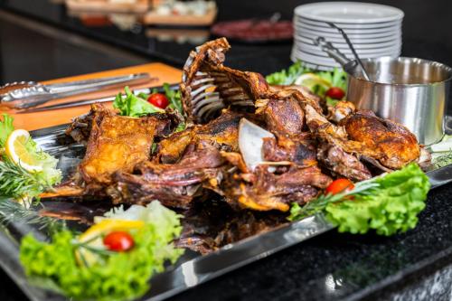 a plate of food with meat and vegetables on a table at Empire Balneo & Spa Hotel in Hisarya
