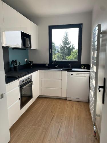 une cuisine avec des armoires blanches et une fenêtre dans l'établissement Close to Paris, for work or family, à Créteil