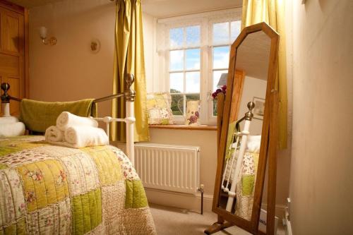 a bedroom with a bed and a mirror and a window at Quiet cottage on the rural edge of Brixham in Brixham