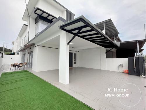 a white house with a green lawn in front of it at Kluang Gunung Lambak view Family Suites in Kluang