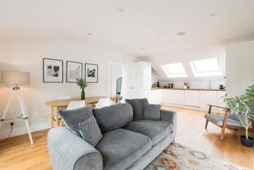 a living room with a gray couch and a kitchen at Contemporary 2 Bed Loft Honor Oak, London Apt in London