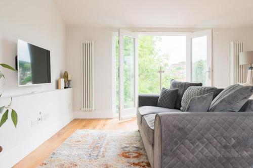 a living room with a gray couch and a tv at Contemporary 2 Bed Loft Honor Oak, London Apt in London