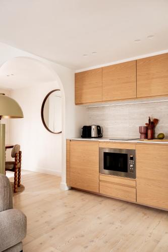 - une cuisine avec des placards en bois et un four micro-ondes dans l'établissement 4P 1BR - Fully Renovated - Step from Place Vendôme, à Paris