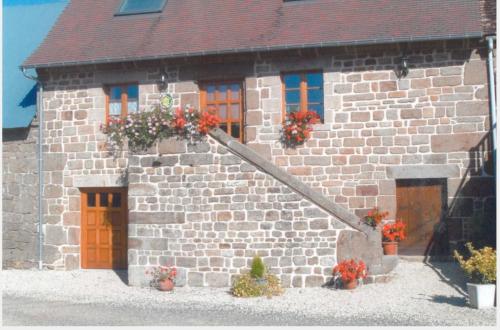 - un bâtiment en briques avec des portes orange et des fleurs dans l'établissement Maison 10p à la campagne, à La Motte-Fouquet