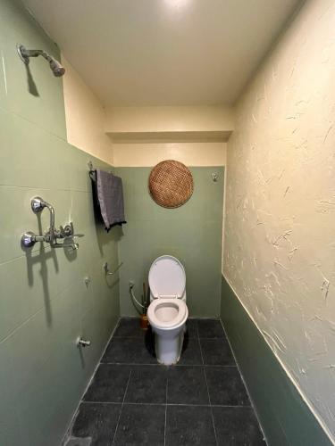 ein Bad mit einem WC in einer grünen Wand in der Unterkunft Sunny and quiet stay in Boudha in Kathmandu