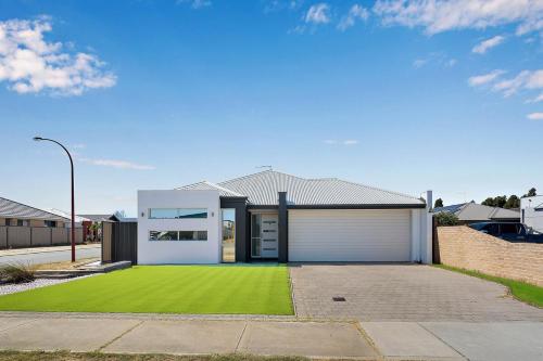 a house with a green lawn in front of it at Spacious 4 Bedroom house in Southern River in Perth